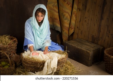 Teenager girl playing the role of the Virgin Mary with a doll in a live Christmas nativity scene