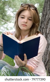 Teenager girl reading book in park