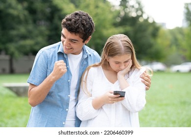 Teenager Girl Receiving Bad News On Phone And Hipocrite Boy Celebrating. Toxic Friendship Concept