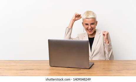 Teenager girl with short hair with a laptop celebrating a victory