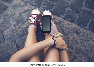 Teenager Girl Sitting With Mobile Phone In Hand, In Ancient Stone Floor