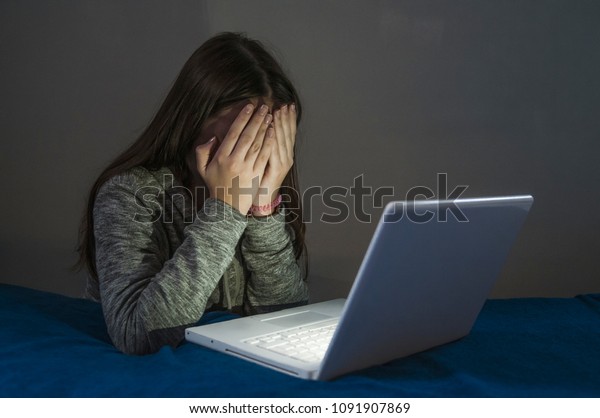 Teenager girl suffering internet cyber bullying\
scared and depressed cyberbullying. Image of despair girl humilated\
on internet by classmate. Young teenage girl crying in front of the\
laptop