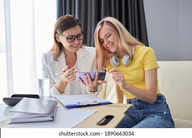 Teenager Girl Talking To School Psychologist, Smiling Student Sitting On The Couch In Office Of Social Worker. Professional Counselor Looks At Smartphone Screen With Student