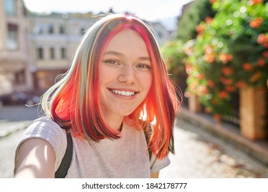 Teenager girl with trendy hairstyle, young fashion art blogger records stream in city, female looks in webcam of smartphone, gestures and talks, close-up face - Powered by Shutterstock