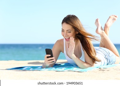 Teenager Girl Waving To The Camera During A Smart Phone Video Call In Vacations With The Sea In The Background