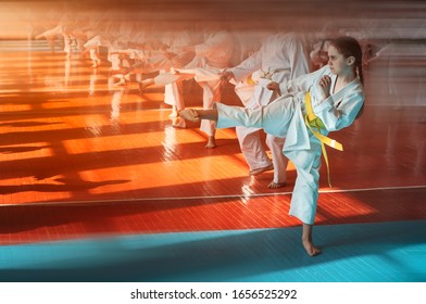 A Teenager Girl With A Yellow Belt In Karate Class Is Doing Stretching. Beautiful Morning Light. Oriental Martial Arts. Children's Training. No Faces. With Place For Text.