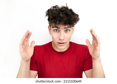 Teenager guy, young man with great surprise on face, emotionally raised hands and uncombed hair on a light background, isolated. Glad guy with a surprise face. Blank for advertising, social post.
