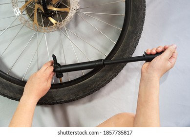 teenager hands holding bicycle pump pumping up bicycle wheel