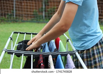 Teenager Hanging Clothes On Drying Rack To Help Out With Household Chores