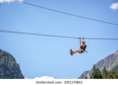 Teenager having fun on a zip line in the Alps, adventure, climbing, via ferrata during active vacations in summer - Shutterstock ID 1051170863