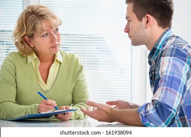 Teenager Having A  Therapy Session While Therapist Is Taking Notes