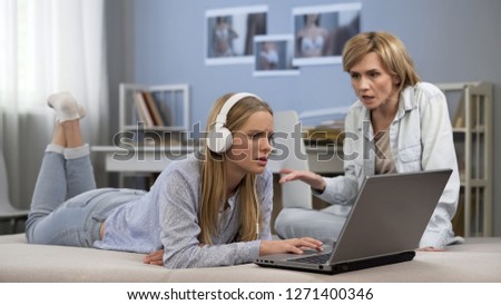 Teenager in headphones ignoring mother, surfing net, difficult puberty age