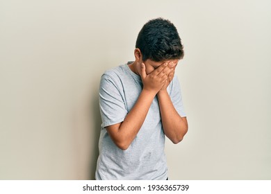 Teenager Hispanic Boy Wearing Casual Grey T Shirt With Sad Expression Covering Face With Hands While Crying. Depression Concept. 