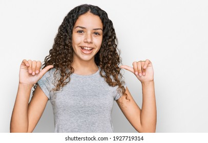 Teenager hispanic girl wearing casual clothes looking confident with smile on face, pointing oneself with fingers proud and happy. 