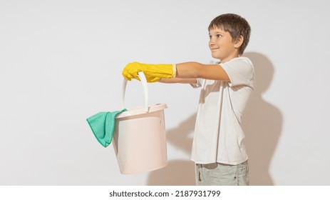 A Teenager Holds A Bucket With Both Hands And Holds It Out, On Outstretched Arms. Cleaning Help Concept.