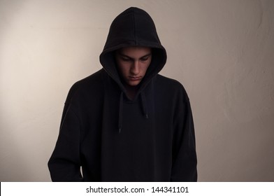 Teenager With Hoodie Looking Down Against A Dirty Gray Wall