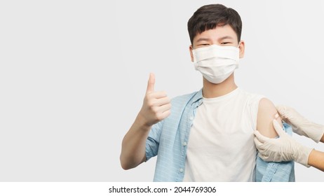 Teenager and kids Covid 19 vaccination concept. Portrait of a healthy smart asian teenager boy with face mask doing thumb up while got mRNA jabs. Back to school, 12-15, Vaccinated, Health pass, Okay.