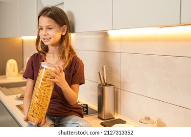 Teenager in the kitchen holding a glass container with pasta