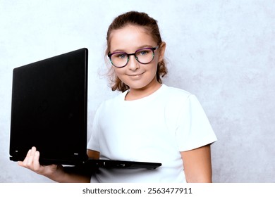 A teenager with a laptop on a light background. A concept of studying and working in the digital world, a modern approach to learning and communication. - Powered by Shutterstock