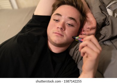 Teenager Laying In Bed With His Vape