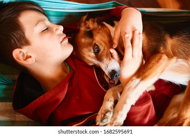 
Teenager  
lies with his dog at home in 
hammock - Shutterstock ID 1682595691