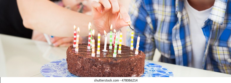 Teenager Lights The Candles On A Birthday Cake
