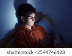 Teenager Lying in Bed at Night Using Smartphone.Teenager using smartphone lying in bed at night, playing games, watching videos, scrolling screen. Children