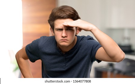 Teenager man looking far away with hand to look something at indoors