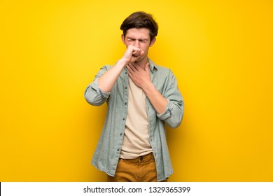 Teenager Man Over Yellow Wall Is Suffering With Cough And Feeling Bad