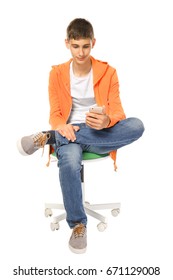 Teenager With Mobile Phone Sitting On Chair Against White Background