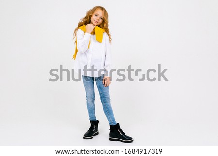teenager model girl in a white shirt and jeans romantically stands on a white isolated background