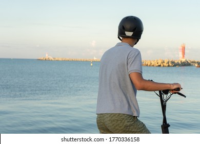 Teenager On Electric Scooter. Teen On The Electric Scooter In Helmet. The Concept Of Safe Movement On A E-scooter