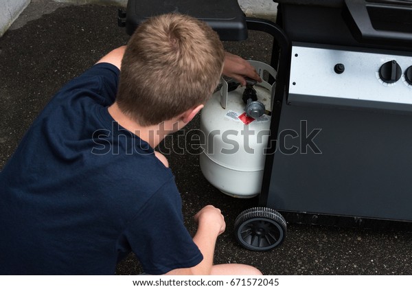 Teenager\
opening a propane tank for a barbecue, Canada.\
