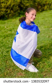 Teenager patriot jewish girl sitting with the flag of Israel wrapped around her. Memorial day-Yom Hazikaron and Yom Ha'atzmaut concept.