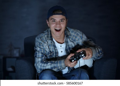 Teenager Playing Videogame At Home Late In Evening