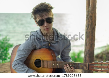 Similar – Young Boy Enjoying Music Playing Guitar Outdoors