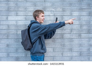 Teenager pointing to something he is recording with his cellphone.