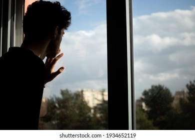 Teenager portrait looking at the window hand on glass