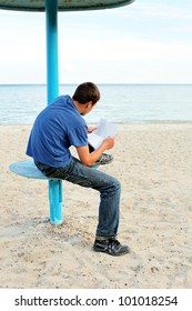 Teenager Reading Letter On The Empty Beach