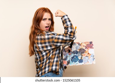 Teenager Redhead Girl Holding A Palette Over Isolated Background Making Strong Gesture