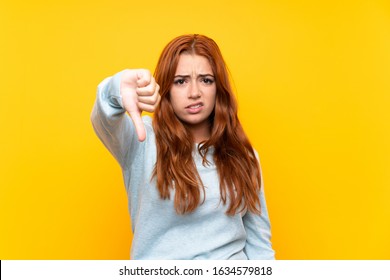 Teenager Redhead Girl Over Isolated Yellow Background Showing Thumb Down With Negative Expression