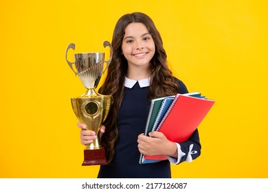 Teenager school girl with award winner trophy. Child hold books with gold trophy or winning cup isolated on yellow. Education graduation, victory and winning.