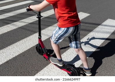 A teenager with a scooter crosses the road at a pedestrian crossing. Road safety. Healthy lifestyle. Eco-friendly transport. - Powered by Shutterstock