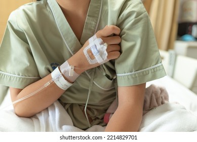 Teenager Sick And In Pain And Uses His Hands To Squeeze His Chest Chest Pain Caused By An Acute Heart Attack With IV Saline Drip To Back Of Hand Lying On Bed In Hospital, Medical And Health Concepts