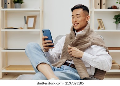 teenager sitting in a chair in a room with phone on his lap - Shutterstock ID 2137023185