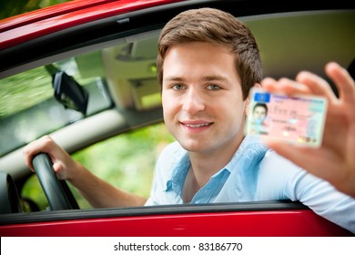 teenager sitting in new car and shows his drivers license