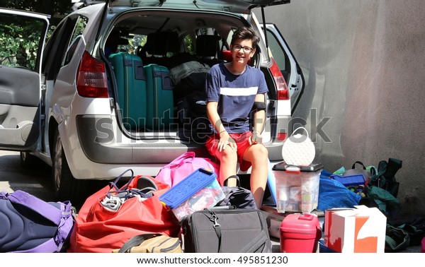 teenager sitting on the car with a lot of\
luggage before leaving for summer\
vacation