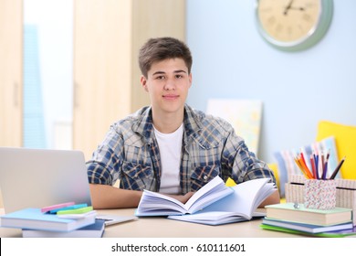 Teenager Sitting At Table And Studying At Home
