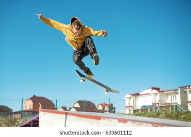 A teenager skateboarder does an flip trick in a skatepark on the outskirts of the city