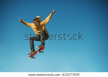 A teenager skateboarder does an ollie trick on background of blue sky gradient